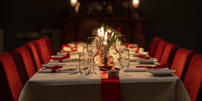 Julbord på Fågelbro Säteri, avsluta året på en lantlig oas på Värmdö 1 Juldukat långbord med levande ljus och röda stolar i en salong på Fågelbro Säteri